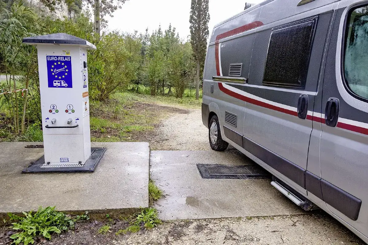 Un camping-car est garé près d'une borne de services Euro-Relais dans un parc.