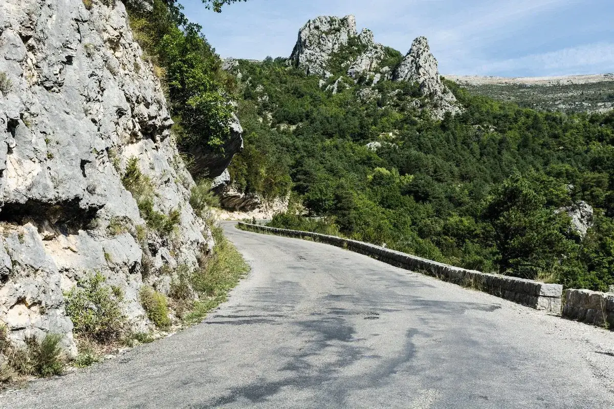 Route Napoléon sinueuse à travers des montagnes verdoyantes et rocheuses. Un chemin historique qui serpente vers des sommets escarpés.