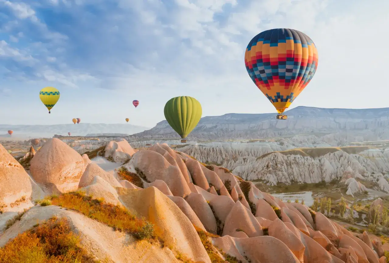 Ballons colorés flottant au-dessus des formations rocheuses uniques de Cappadoce, un paysage emblématique du tourisme en Turquie.