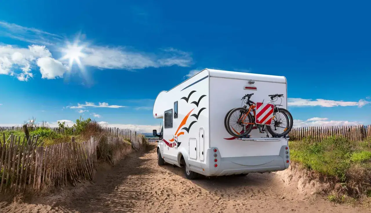 Camping-car prêt pour l'aventure sur une aire de camping car Île de Ré, avec vélos à l'arrière, sous un ciel bleu éclatant.