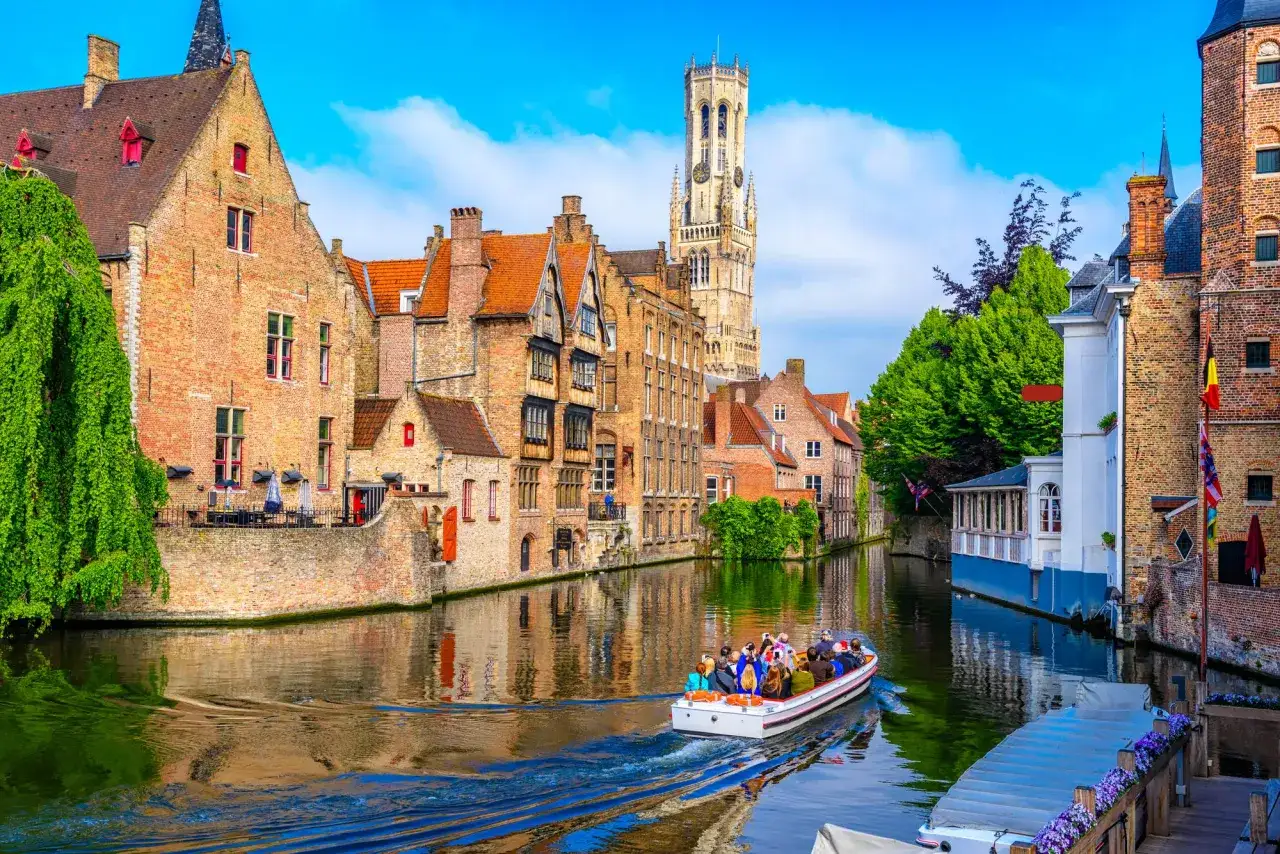 Une balade en bateau sur les canaux, une id&eacute;e parfaite pour savoir que faire &agrave; Bruges. Les maisons historiques et le beffroi se refl&egrave;tent dans l'eau.