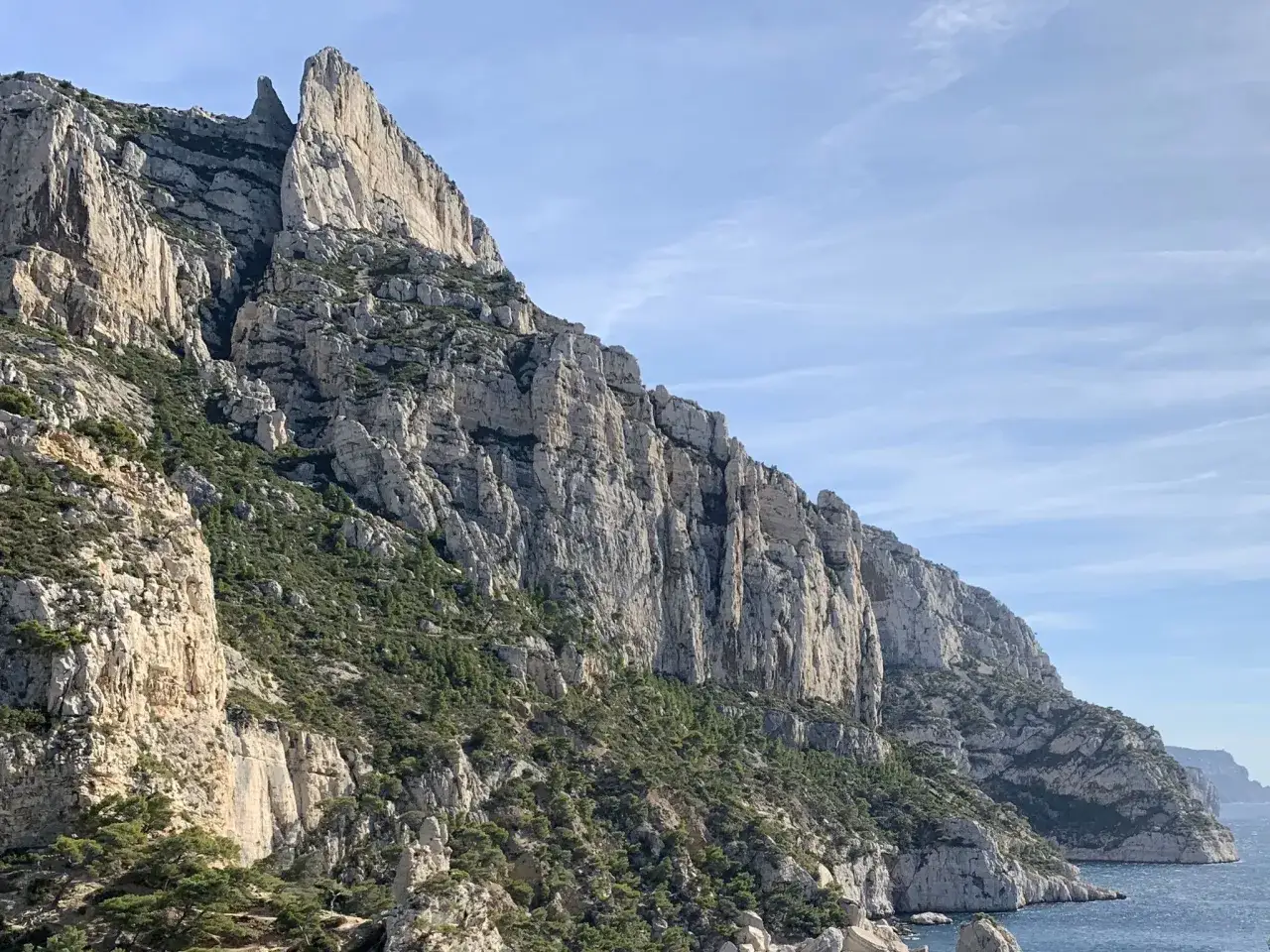 Le Mont Puget se dresse, imposant, ses falaises calcaires plongeant vers la mer bleue sous un ciel clair.