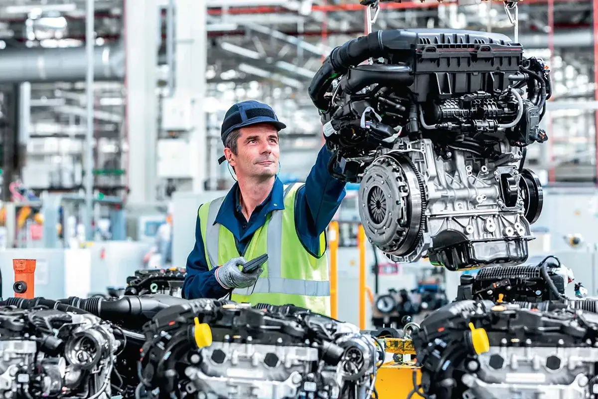Un technicien examine un moteur Citroën Jumper 2.2 HDI 140 CV dans une usine. Avis sur ce moteur : performance et fiabilité.