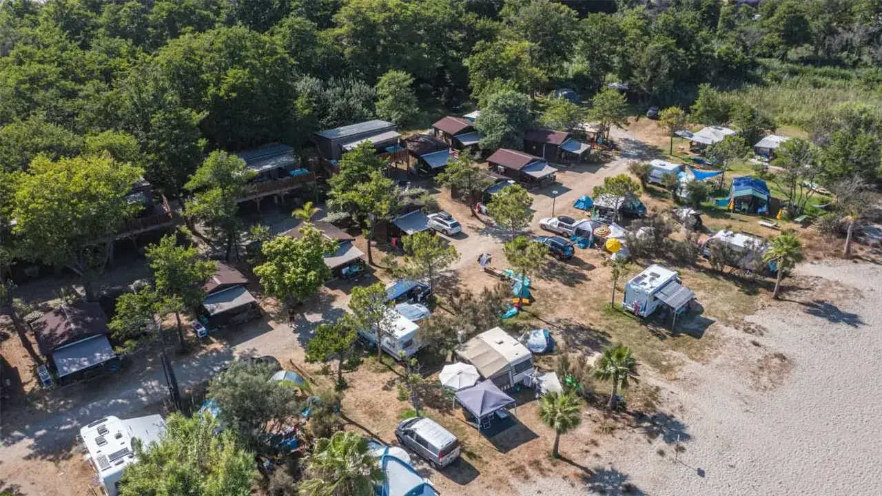Vue a&eacute;rienne d'un camping en Corse, avec des mobil-homes, tentes et camping-cars. Une sc&egrave;ne paisible, loin de toute agression.