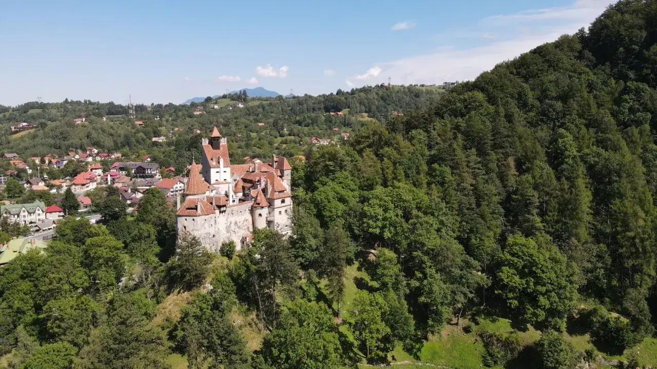 Château de Bran, un lieu emblématique pour une randonnée en Roumanie, perché sur une colline boisée.