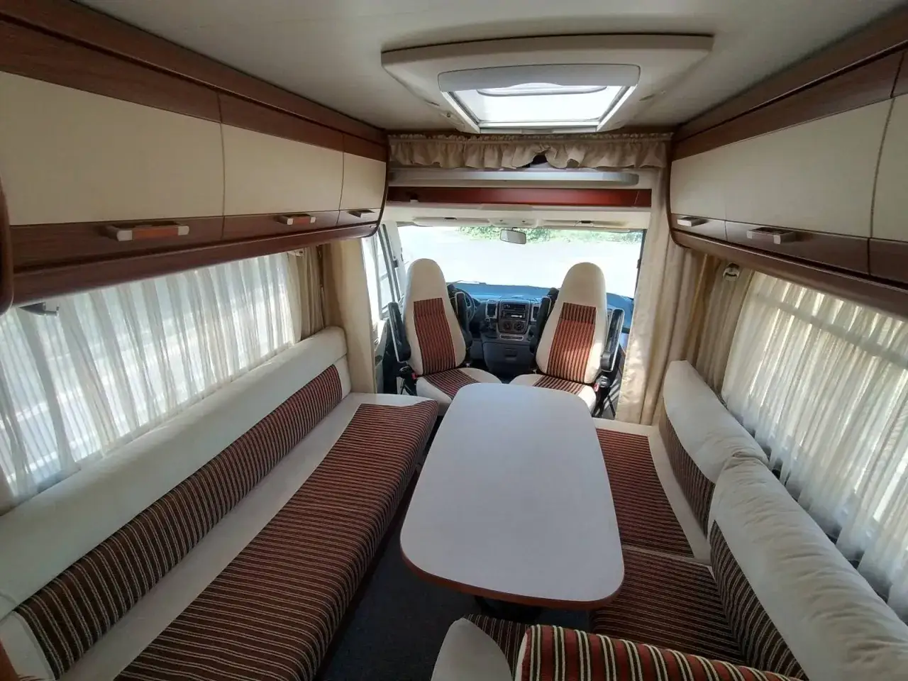 Int&eacute;rieur d'un camping-car Hymer B544, avec banquettes, table et si&egrave;ges de cabine. Id&eacute;al pour consulter la fiche technique.