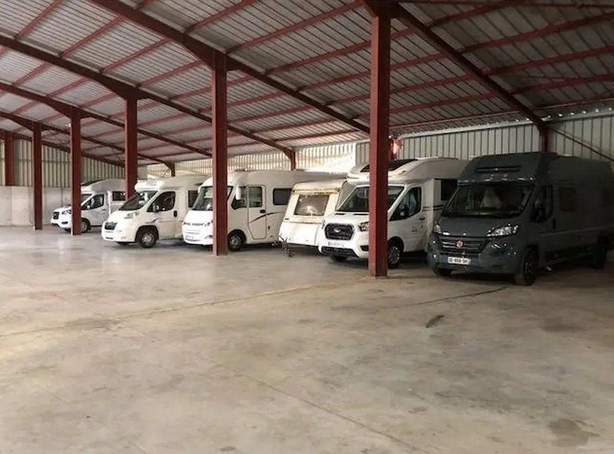 Plusieurs camping-cars et une caravane sont gar&eacute;s dans un entrep&ocirc;t, pr&ecirc;ts pour leur hivernage.