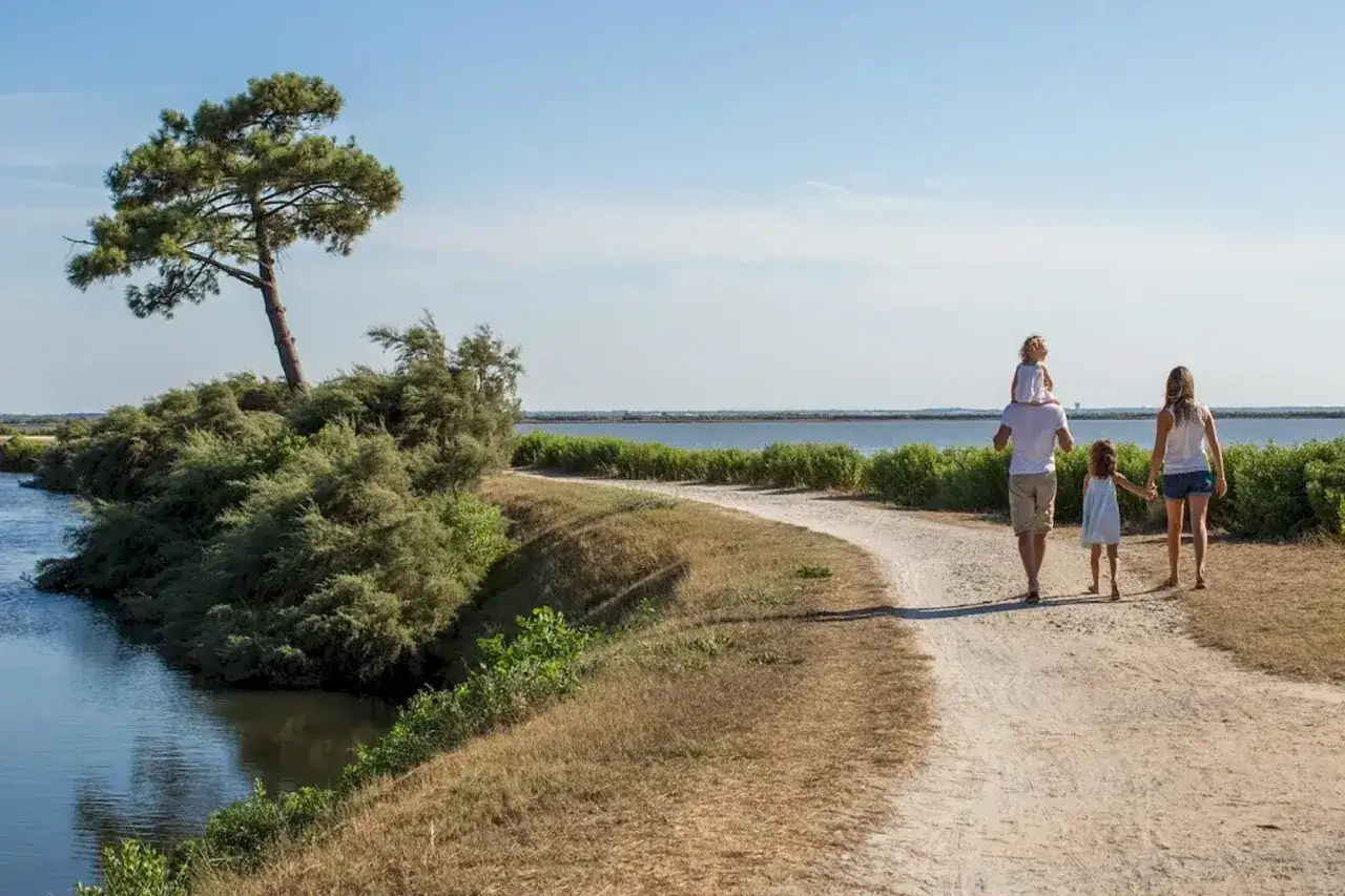 Famille en randonnée à Arcachon, profitant d'une promenade en bord de mer sous un ciel bleu.