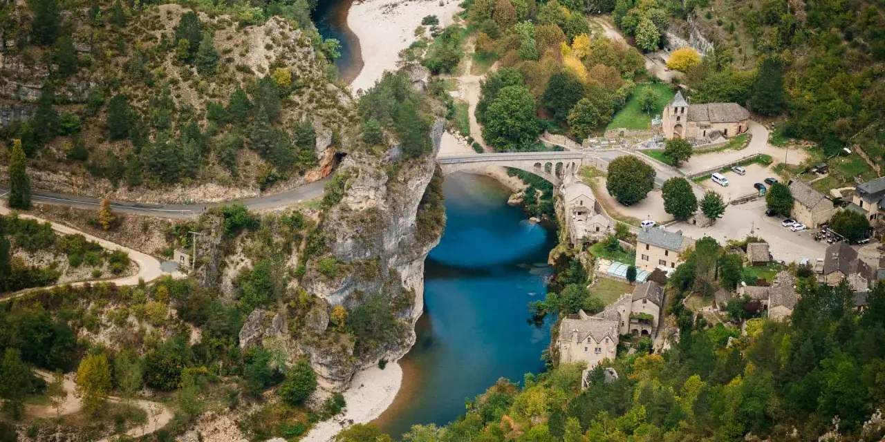 Vue a&eacute;rienne des gorges du Tarn, avec un village pittoresque, un pont ancien et une rivi&egrave;re bleue. Une carte id&eacute;ale pour planifier votre visite.