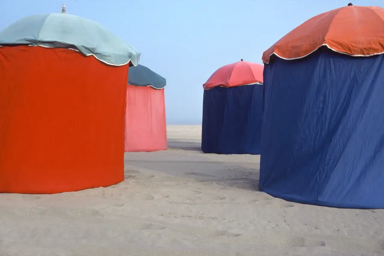 Cabines de plage colorées sur la plage de Deauville, sous un ciel bleu clair.