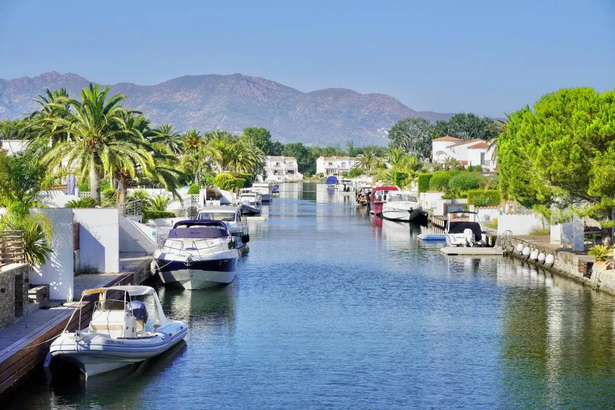 Canal pittoresque &agrave; Empuriabrava, Espagne, bord&eacute; de maisons blanches, de palmiers et de bateaux amarr&eacute;s.