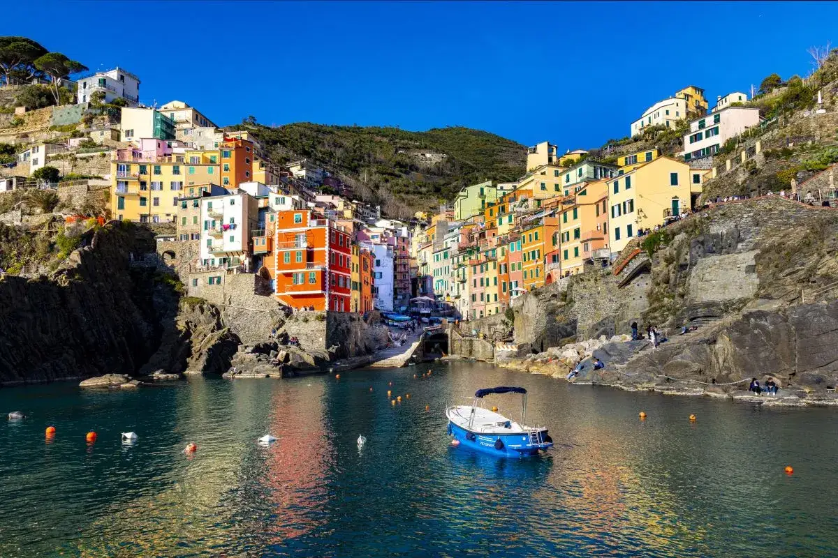 Les 5 Terres en camping-car : un village coloré accroché à la falaise, avec un bateau bleu dans le port.